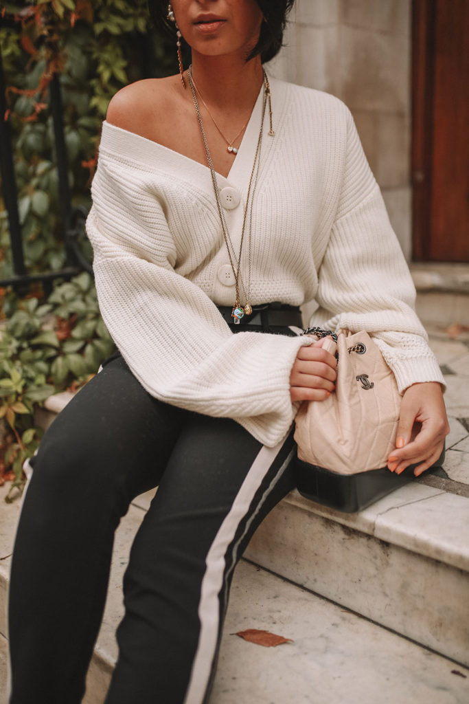 Luxury fashion blogger Shoka Narang of The Silk Sneaker shares how to style an oversized knit cardigan for a cute winter outfit with & Other Stories, Chanel backpack and Gucci Sneakers