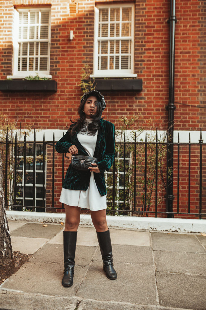 Luxury fashion blogger Shloka Narang of The Silk Sneaker shares how to wear a belt bag with a Prada belt bag, ASOS dress and velvet blazer for a winter outfit