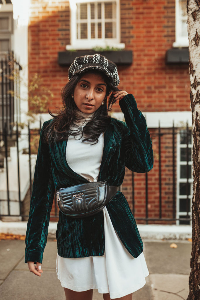 Luxury fashion blogger Shloka Narang of The Silk Sneaker shares how to wear a belt bag with a Prada belt bag, ASOS dress and velvet blazer for a winter outfit