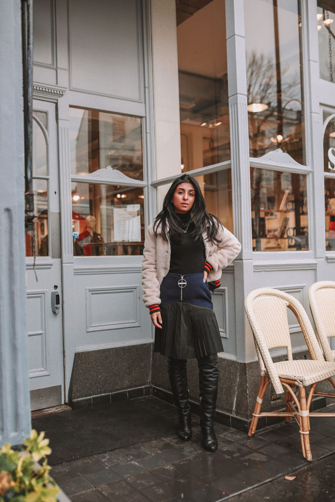 Luxury fashion blogger Shloka Narang of The Silk Sneaker shares how to style a pleated skirt in the winter for a casual outfit featuring Givenchy and Farfetch
