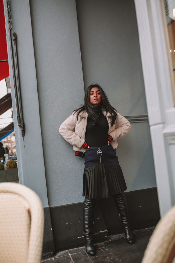 Luxury fashion blogger Shloka Narang of The Silk Sneaker shares how to style a pleated skirt in the winter for a casual outfit featuring Givenchy and Farfetch