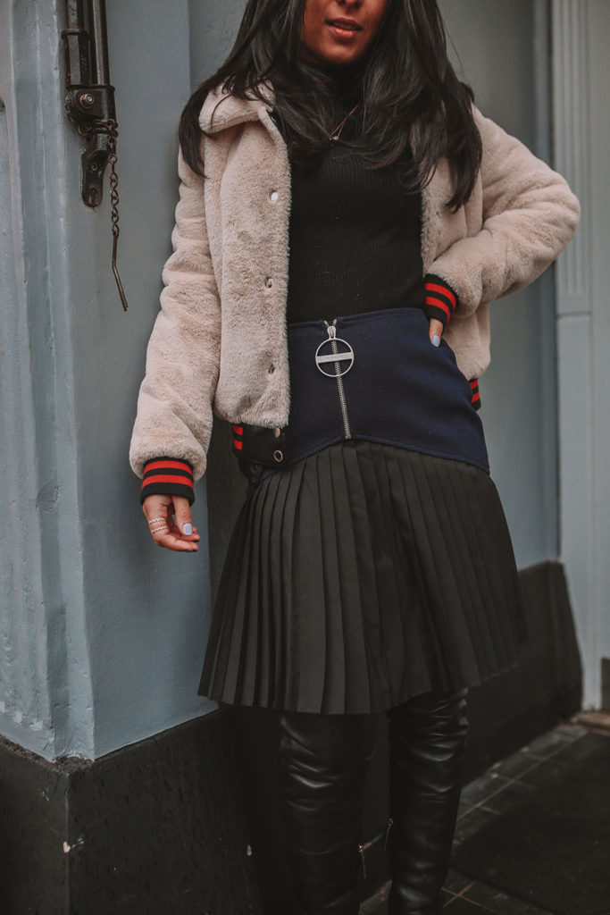 Luxury fashion blogger Shloka Narang of The Silk Sneaker shares how to style a pleated skirt in the winter for a casual outfit featuring Givenchy and Farfetch