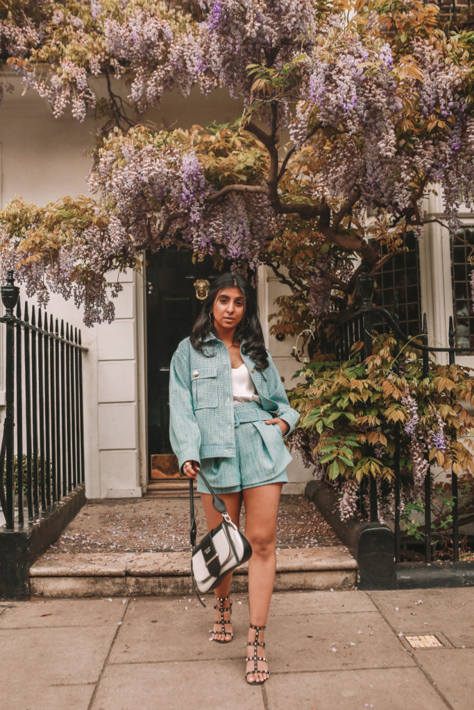 Luxury fashion blogger Shloka Narang of The Silk Sneaker shows how to style matching sets in a Maje coord suit, Prada bag and Valentino Sandals in London with Wysteria