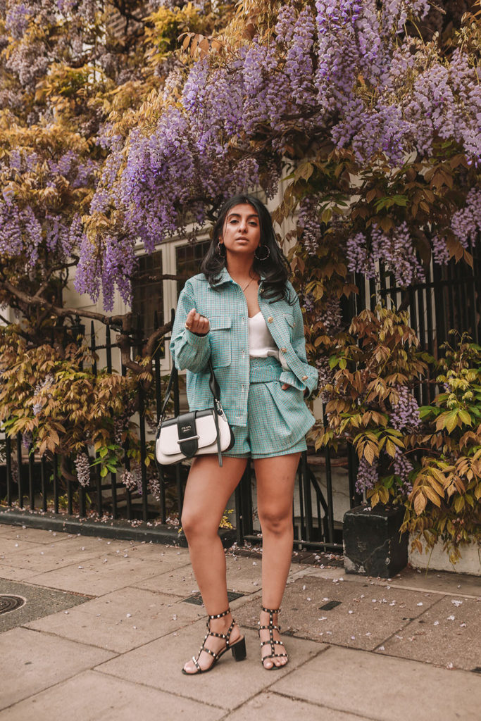 Luxury fashion blogger Shloka Narang of The Silk Sneaker shows how to style matching sets in a Maje coord suit, Prada bag and Valentino Sandals in London with Wysteria