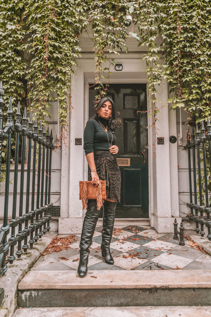Luxury fashion blogger Shloka Narang of The Silk Sneaker shares a zebra print outfit in a ba&sh zebra print skirt with a turtleneck and thigh high boots