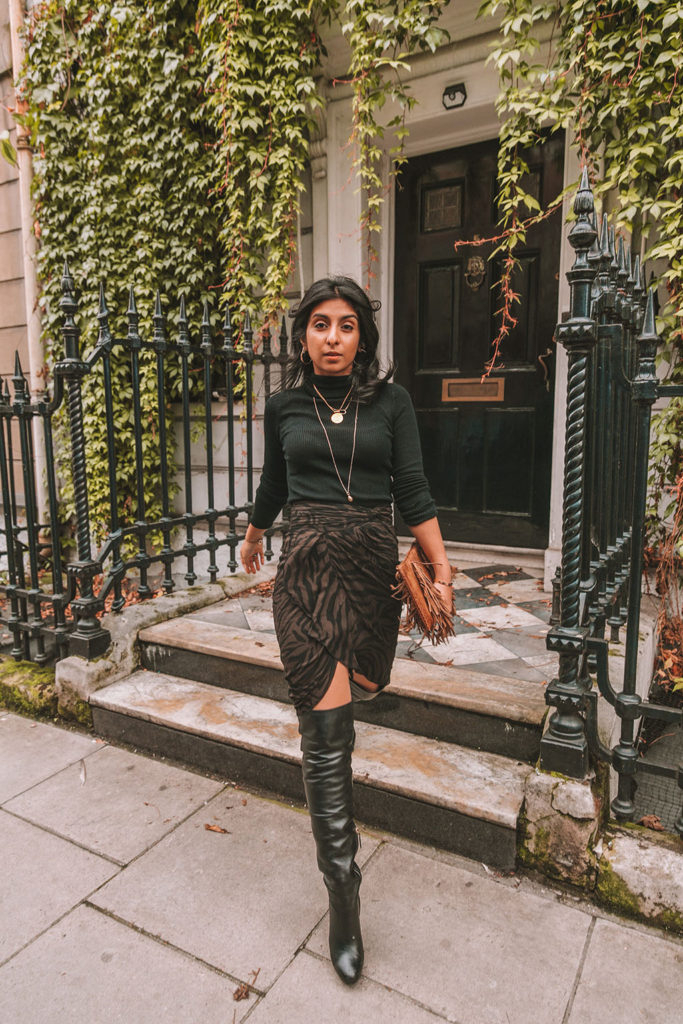 Luxury fashion blogger Shloka Narang of The Silk Sneaker shares a zebra print outfit in a ba&sh zebra print skirt with a turtleneck and thigh high boots