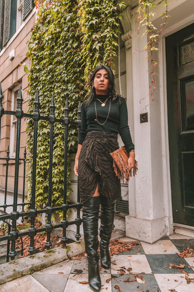 Luxury fashion blogger Shloka Narang of The Silk Sneaker shares a zebra print outfit in a ba&sh zebra print skirt with a turtleneck and thigh high boots