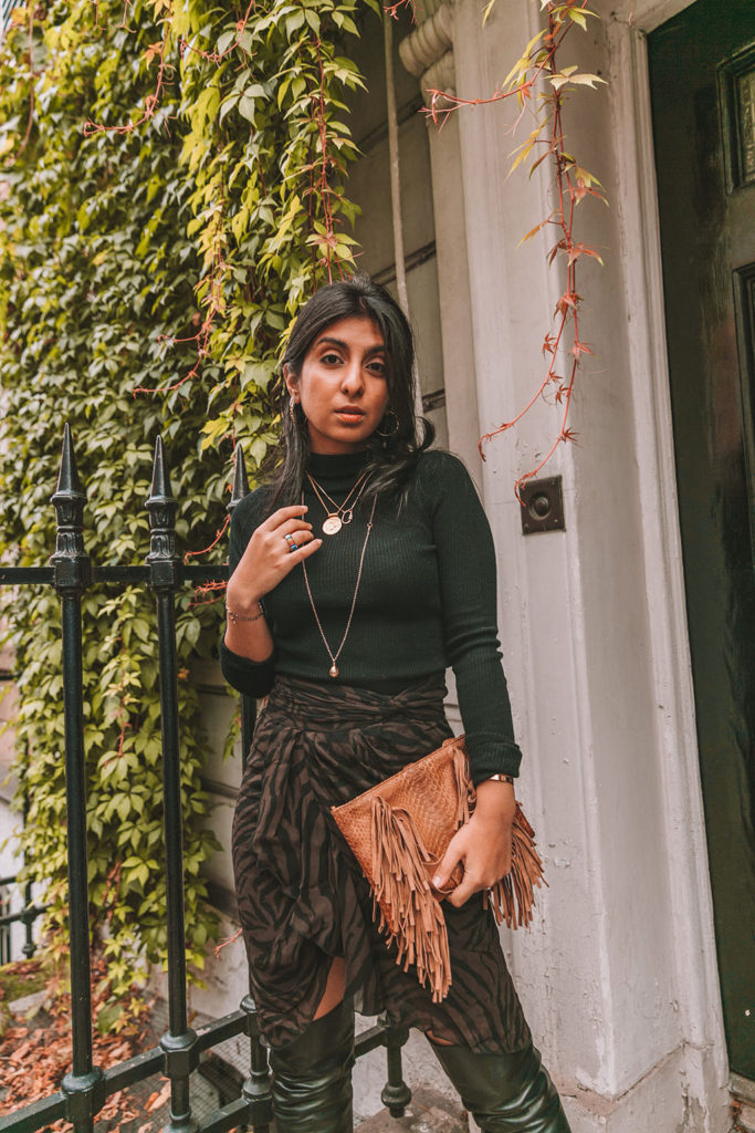 Luxury fashion blogger Shloka Narang of The Silk Sneaker shares a zebra print outfit in a ba&sh zebra print skirt with a turtleneck and thigh high boots