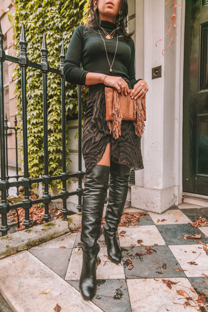 Luxury fashion blogger Shloka Narang of The Silk Sneaker shares a zebra print outfit in a ba&sh zebra print skirt with a turtleneck and thigh high boots