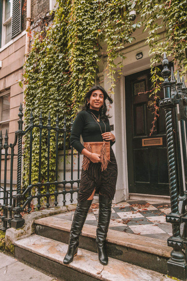 Luxury fashion blogger Shloka Narang of The Silk Sneaker shares a zebra print outfit in a ba&sh zebra print skirt with a turtleneck and thigh high boots