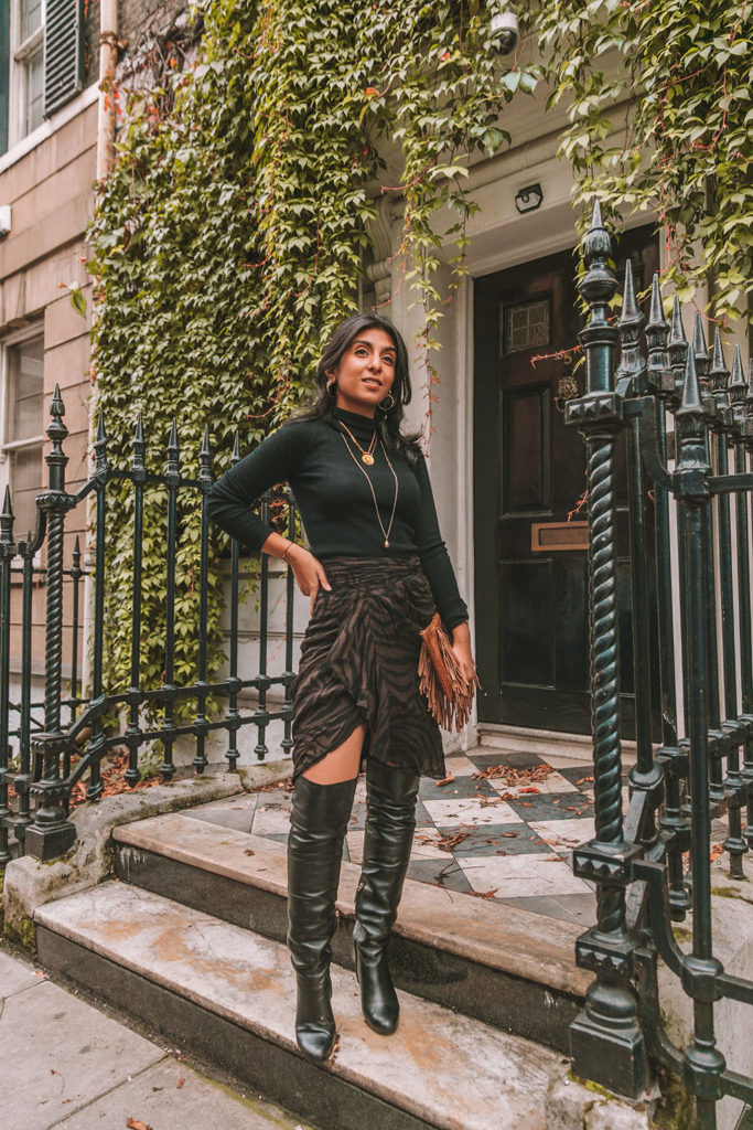 Luxury fashion blogger Shloka Narang of The Silk Sneaker shares a zebra print outfit in a ba&sh zebra print skirt with a turtleneck and thigh high boots