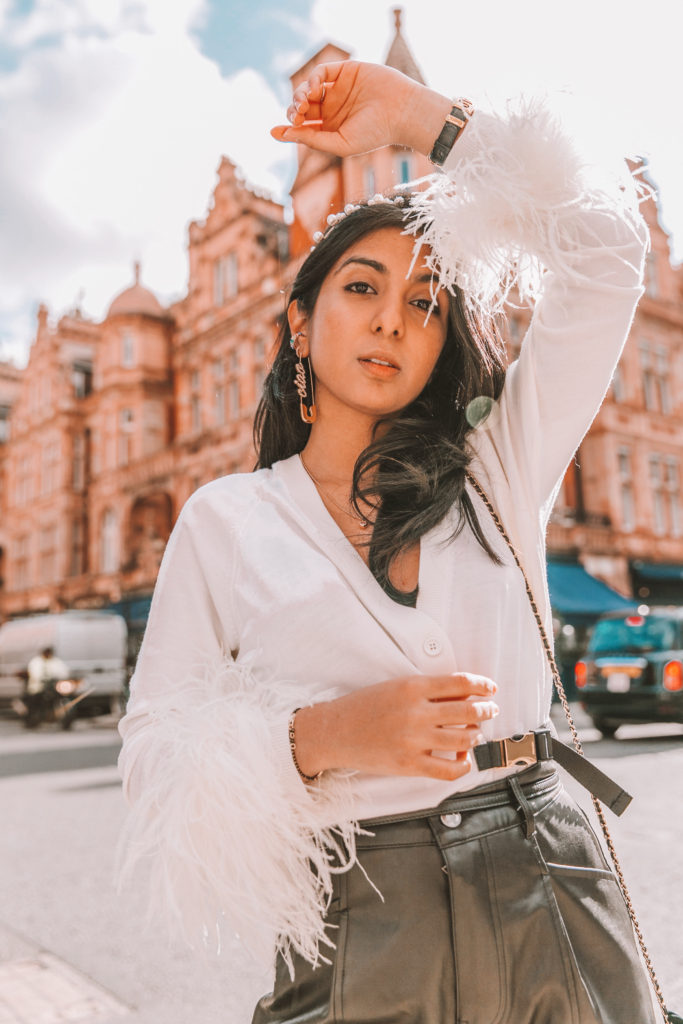 Luxury fashion blogger Shloka Narang of The Silk Sneaker shows how to style fall winter fashion trend of feathers wearing Prada sweater and Zara faux leather trousers